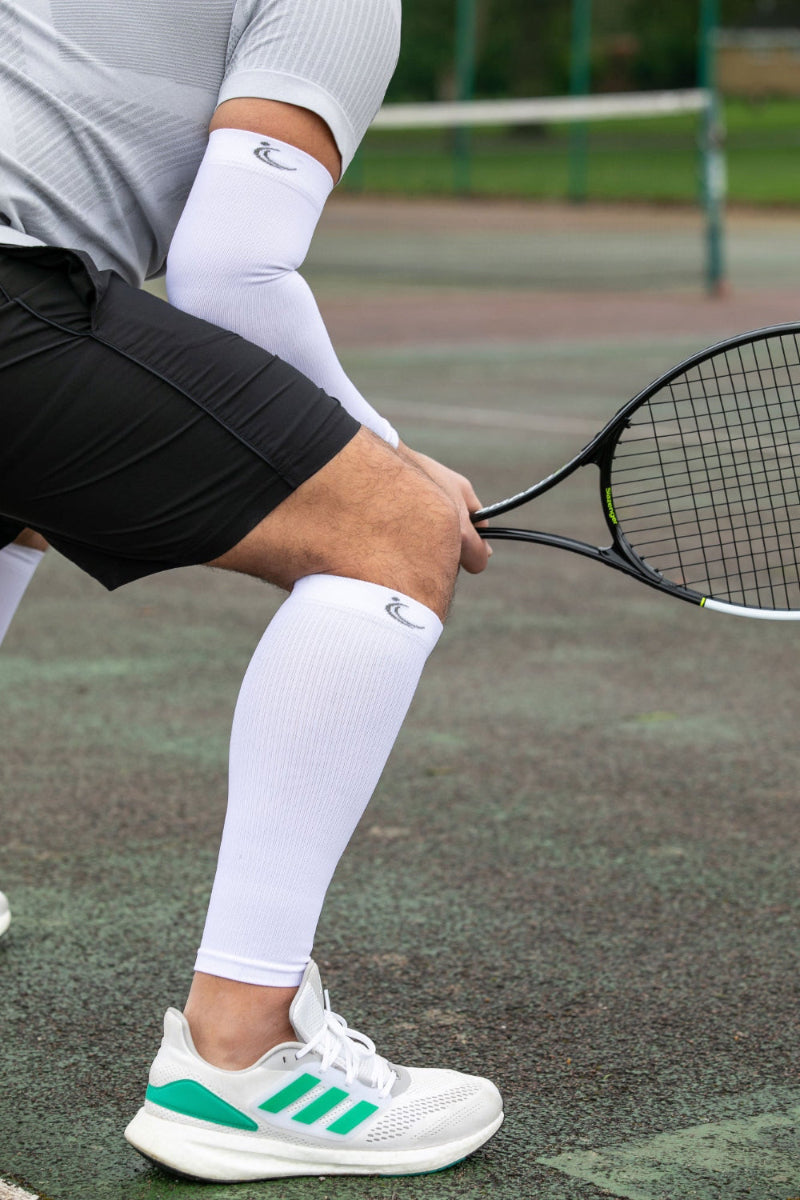 Tennis player wearing FITLEGs calf compression sleeve and a white arm compression sleeve.