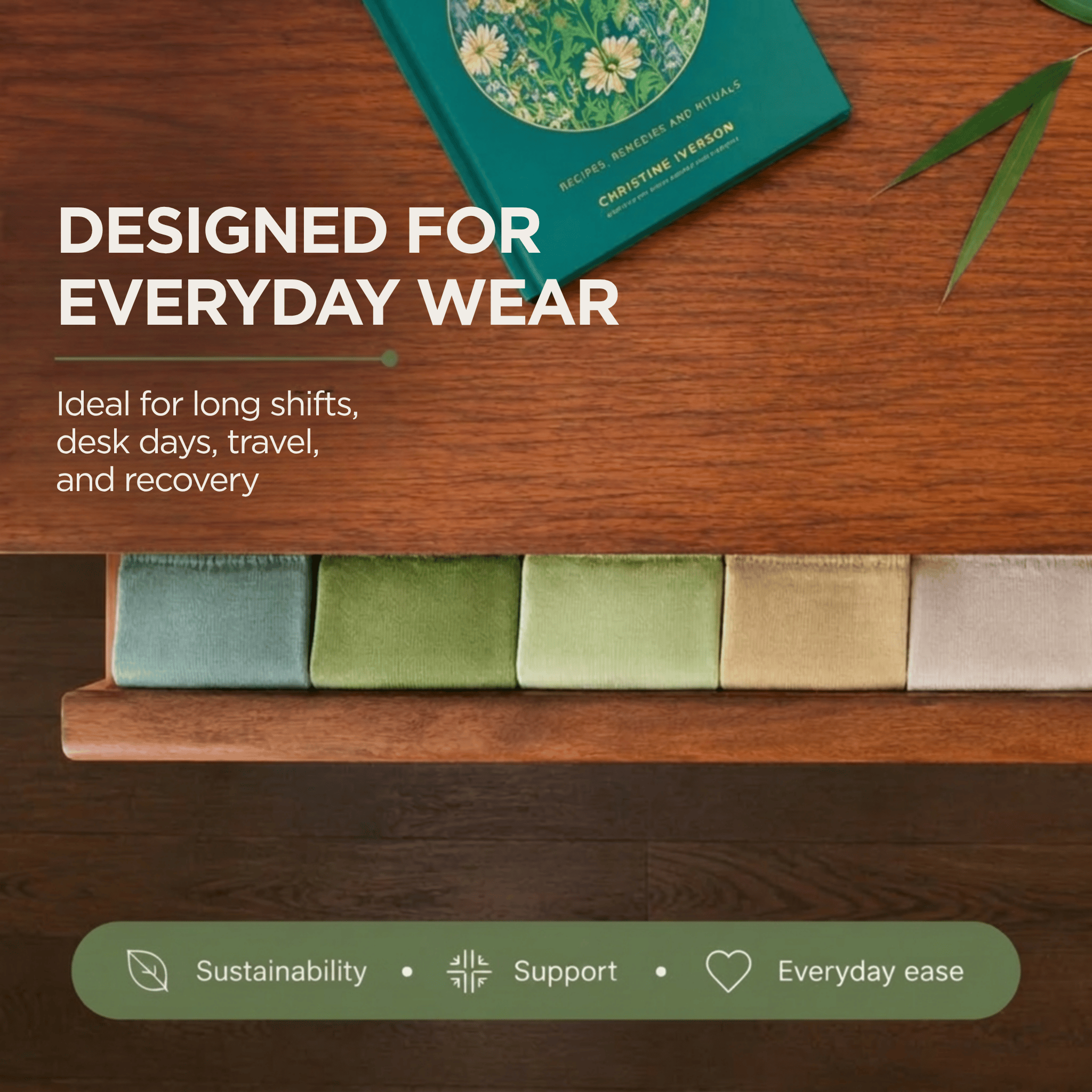 A styled flat-lay on a wooden surface showing a teal book, green bamboo leaves, and a row of folded compression socks  in muted green, beige, and cream. Large text reads 'DESIGNED FOR EVERYDAY WEAR' with smaller copy below, and a green banner at the bottom says 'Sustainability • Support • Everyday ease'.